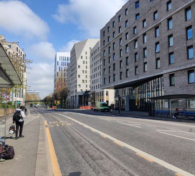 Lewes Road in Brighton with a bus stop, a cycle lane and modern blocks of flats on the right