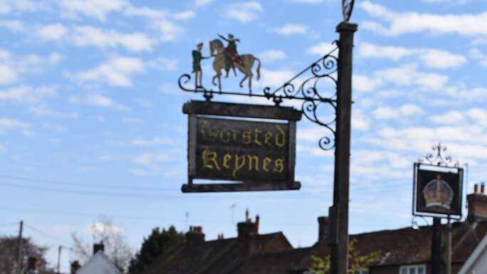 The hanging village sign for Horsted Keynes showing a figure on horseback, against a blue sky with cloud