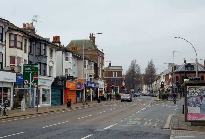 London Road near Preston Circus in Brighton, with a row of shops on the left and a bus lane in the foreground