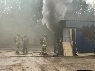 Firefighters working near a smoking metal shed during training