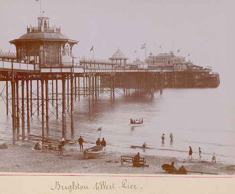 Old album photograph of the West Pier with boats on the beach
