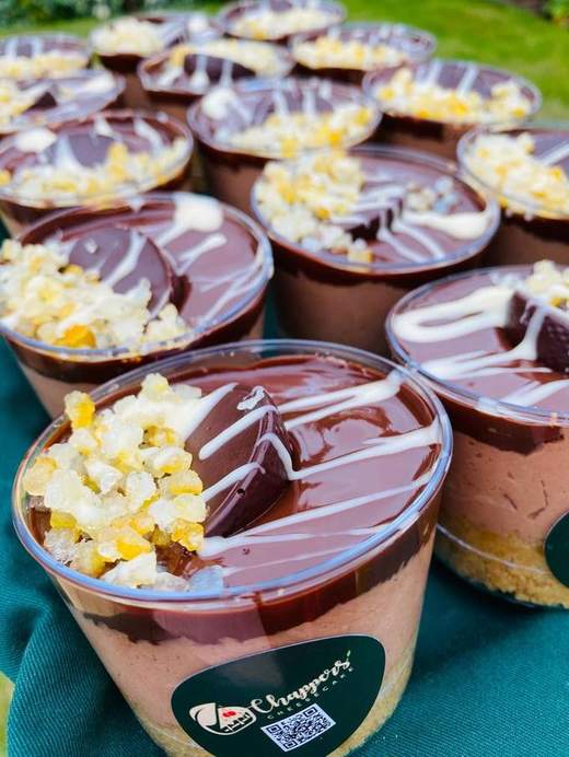 Dessert pots topped with popcorn and a white drizzle on a green cloth