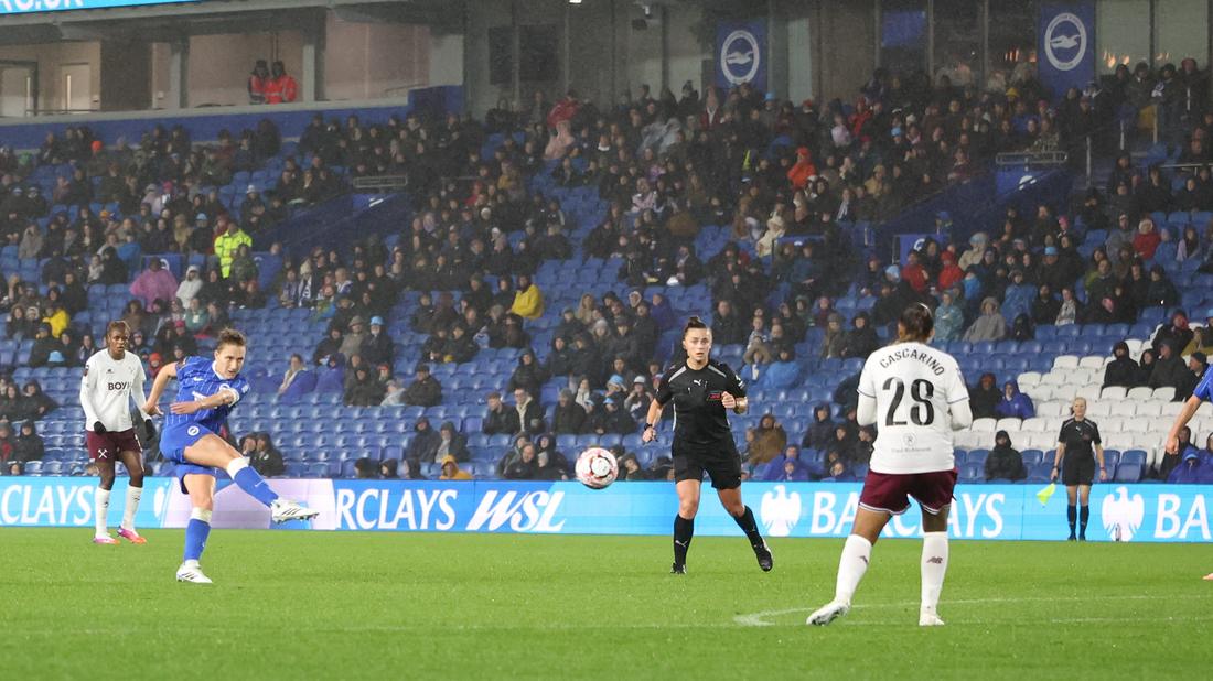 Albion Women in blue attacking in heavy rain against West Ham United in front of a large crowd at the Amex on 24 October 2026