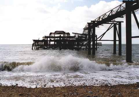 A wave breaking on the beach with the pier ruin behind in 2005