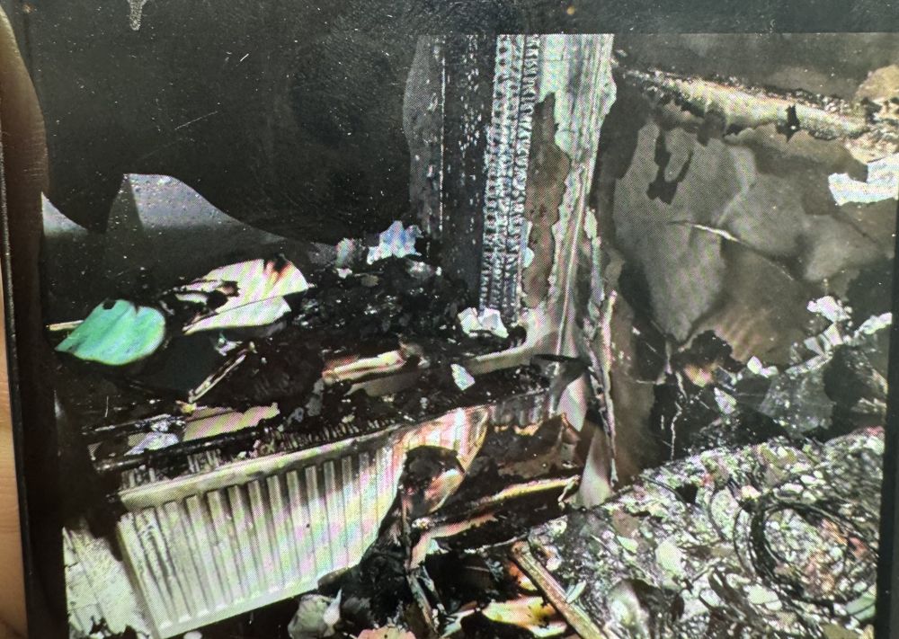 A room badly damaged by fire, with burnt furnishings and charred walls around a radiator