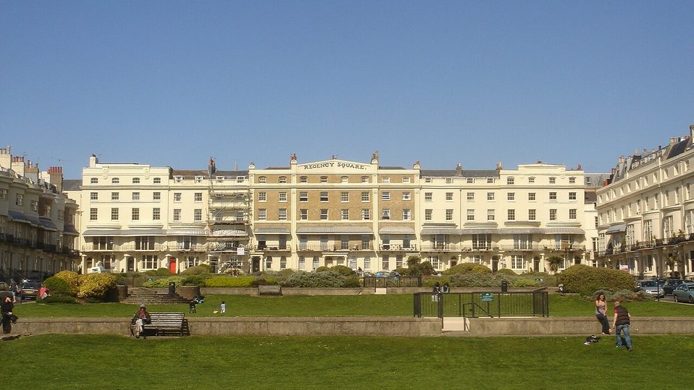 Cream and white Regency terraces around Regency Square in Brighton, with people on the lawn in front