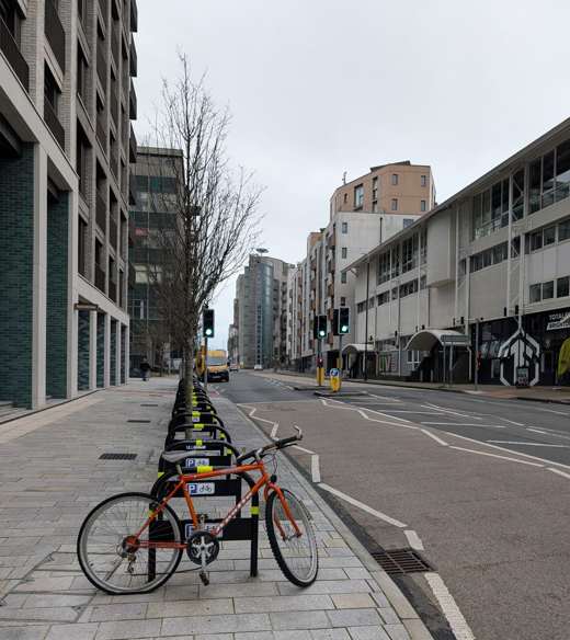 New England Street in Brighton, with modern flats on the left, a row of cycle hire bikes and a tree-lined pavement