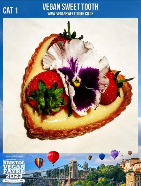 A vegan tart topped with fresh strawberries and an edible pansy flower