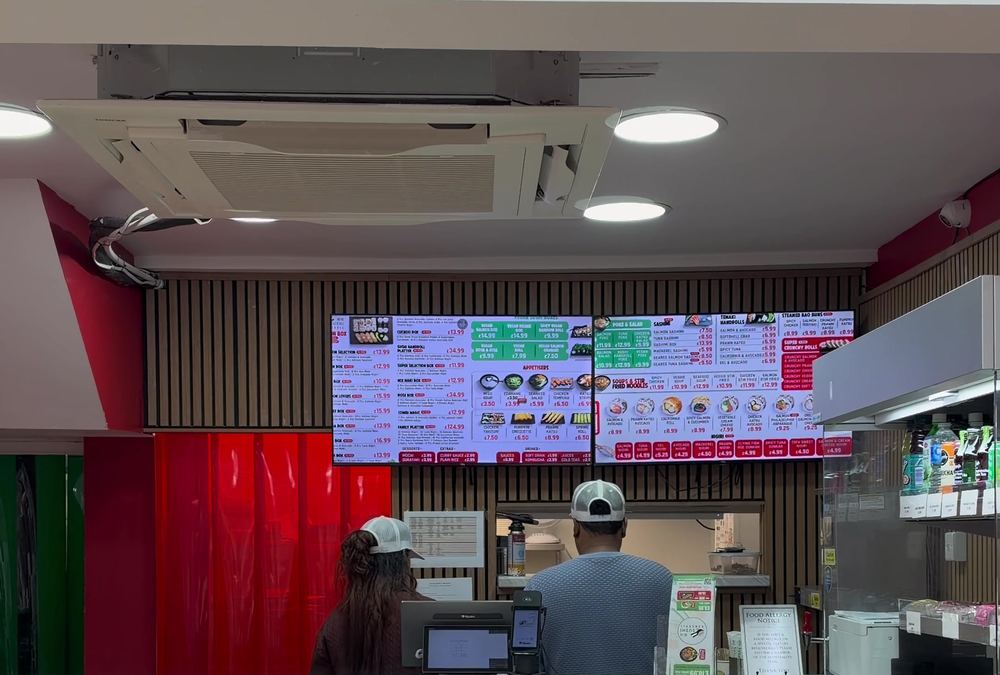 Inside Sushi Handroll in Brighton, with the ordering counter and digital menu boards on the back wall