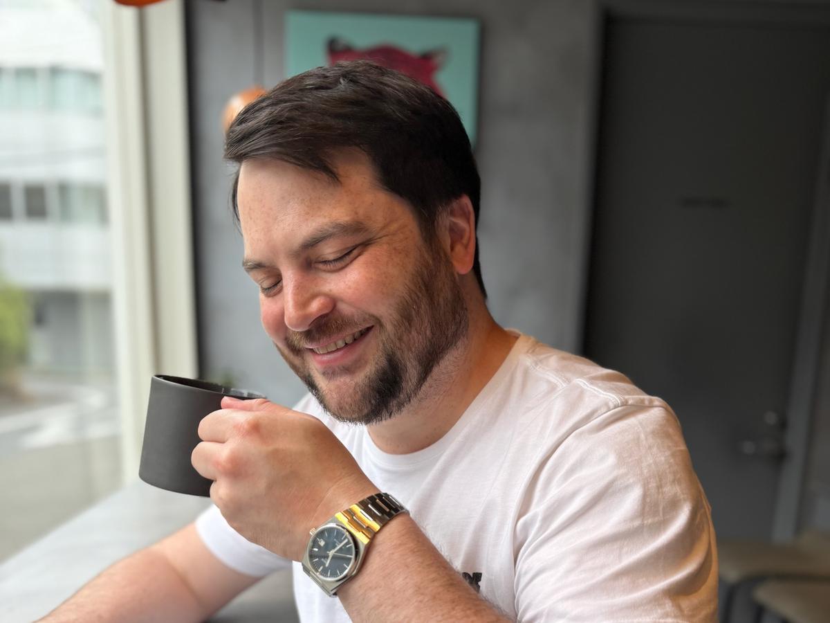 Erik Selby looking down and smiling as he holds a dark mug