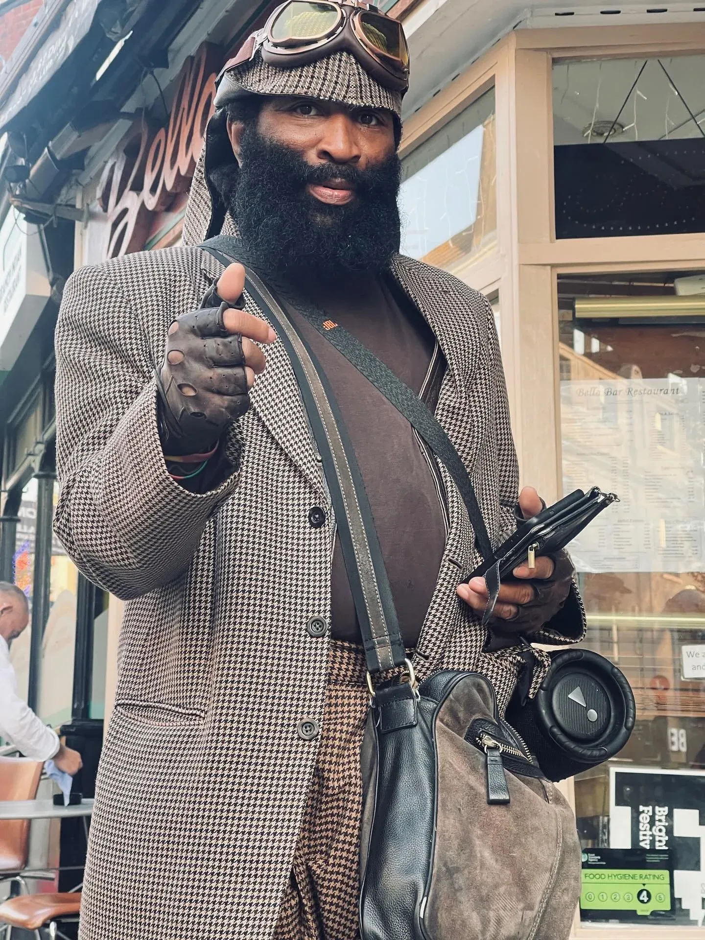 Charles Pirate Saddler in a houndstooth suit and goggles with his speaker on a Brighton street