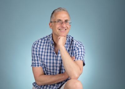 Tim Barford, founder of VegfestUK, smiling with his chin on his hand against a pale blue background